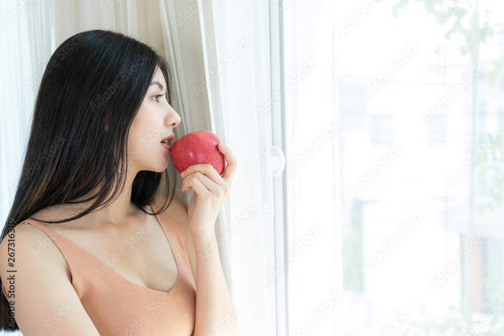Beautiful beauty sexy Asian woman slim holding red apple on white bedroom background Beautiful beauty sexy Asian woman slim holding red apple on white bedroom background