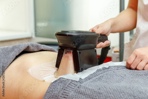 Cryolipolysis freeze fat procedure in cosmetic salon, belly close-up photo
