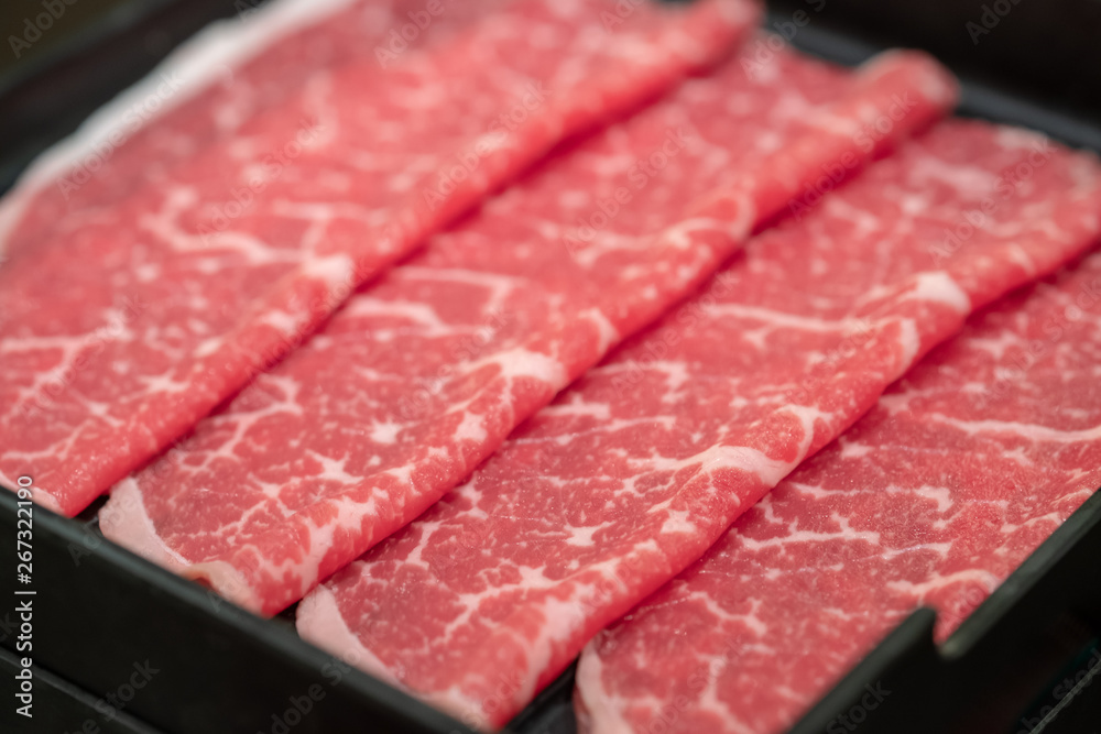 Close up of raw meat in black tray.
