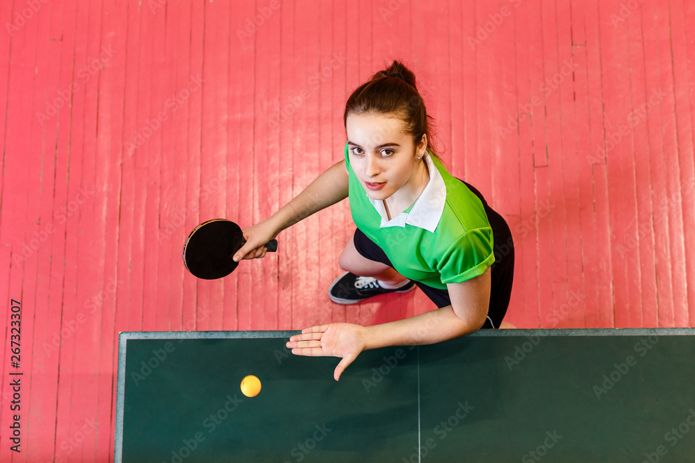 beautiful teen girl plays ball in table tennis. Teens and ping pong