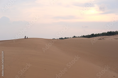 young woman relaxing at white sand dunes on sunset background