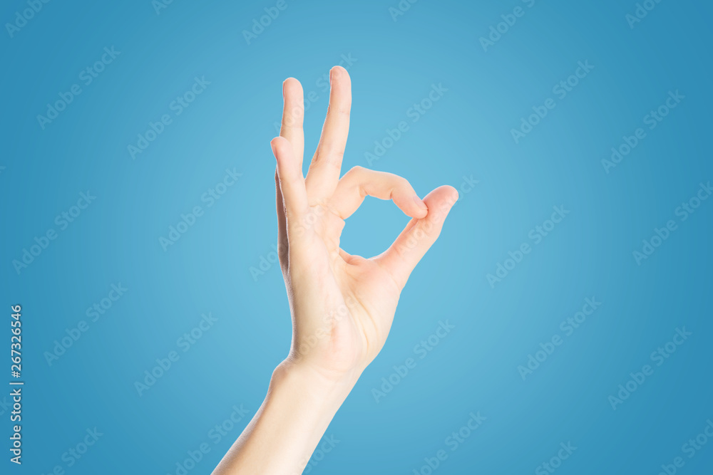 Positive gesture on a blue background. Hand show okay sign, close up Positive gesture on a blue background. Hand show okay sign, close up