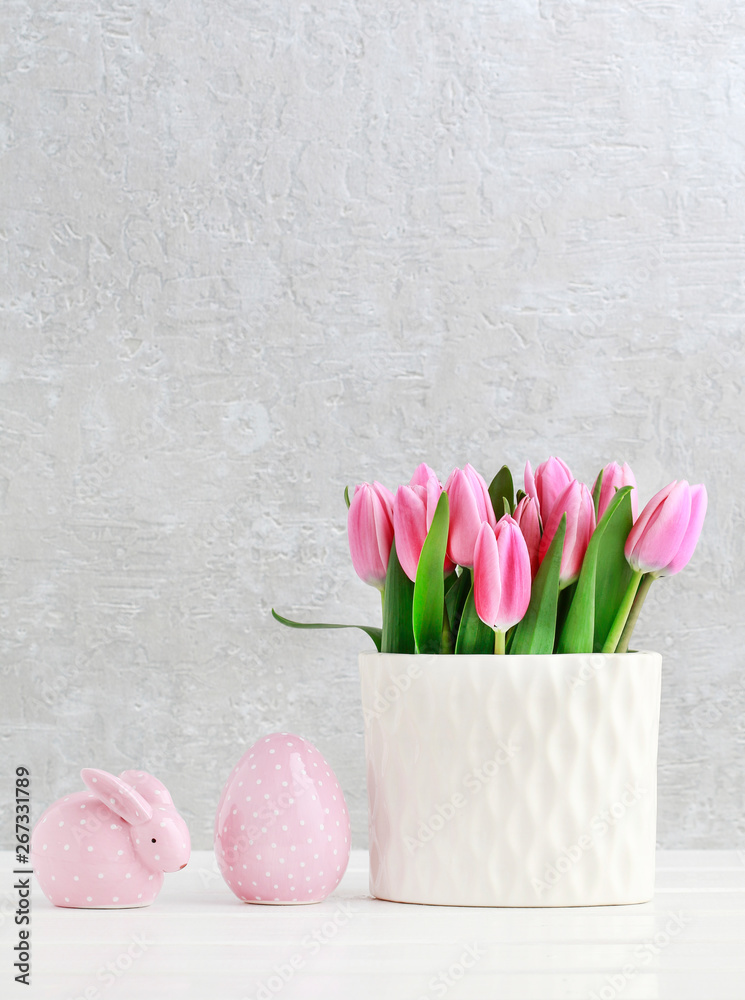 Beautiful pink tulips in ceramic vase, dotted rabbit and Easter egg.