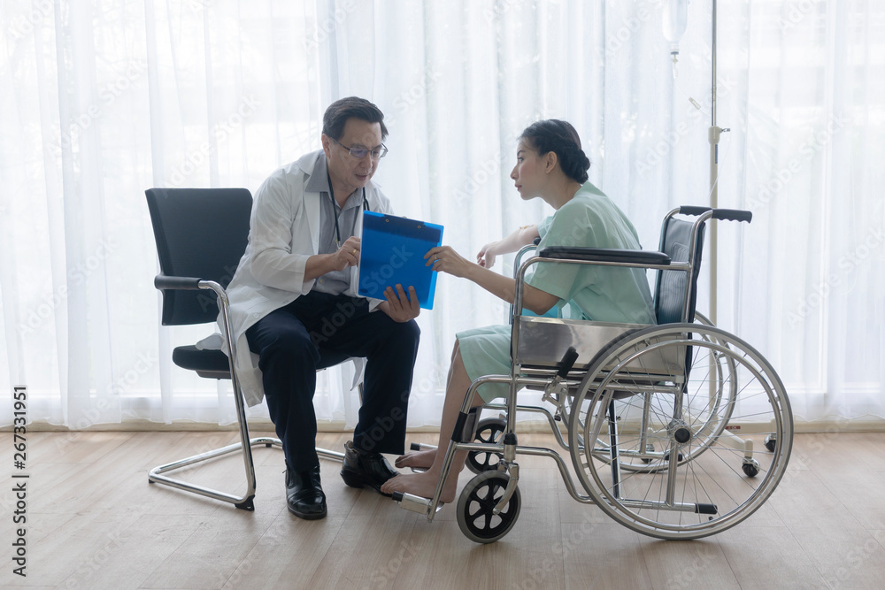 The senior male doctor talked and inquired about the patient's illness at the wheelchair of the patient. The senior male doctor talked and inquired about the patient's illness at the wheelchair of the patient.