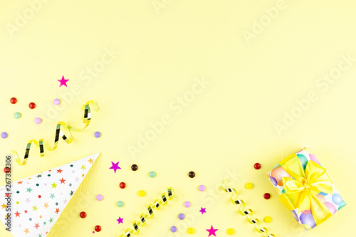 Birthday party background with wrapped gifts, confetti, party hats, decorations, top view