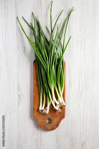 Fresh green onions on a cutting board on a white wooden background  top view. From above  overhead  flat lay.