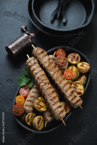 Grilled chicken kebabs with mini potatoes and cherry tomatoes, vertical shot, closeup