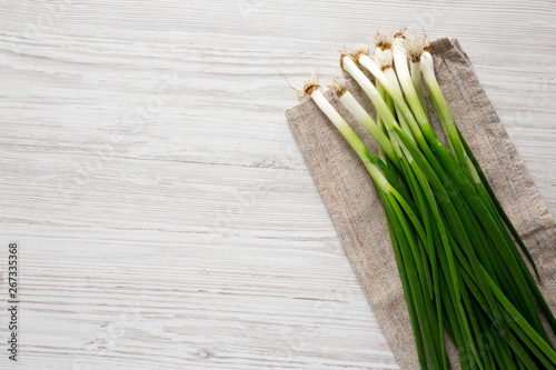 Fresh green onions on a white wooden surface  overhead view. From above  top view  flat lay. Copy space.