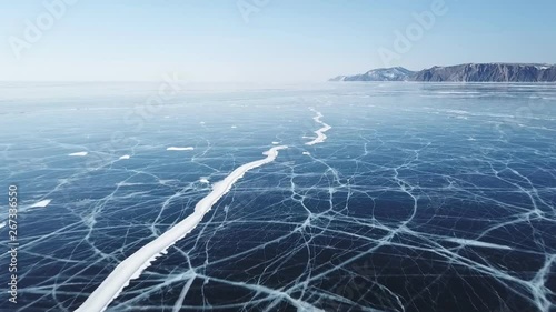 Drone rises above the frozen crystal ice of the lake Baikal. Top view. Natural background and patterns