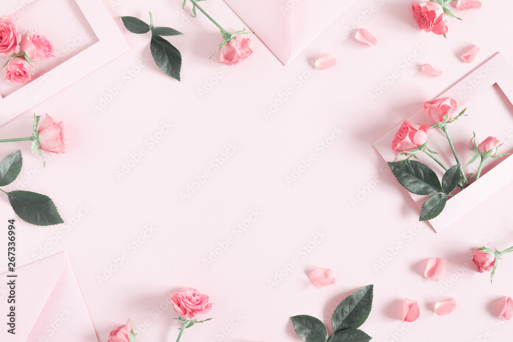 Flowers composition romantic. Pink envelopes and flowers roses, rose petals on pastel pink background. Flat lay, top view, copy space
