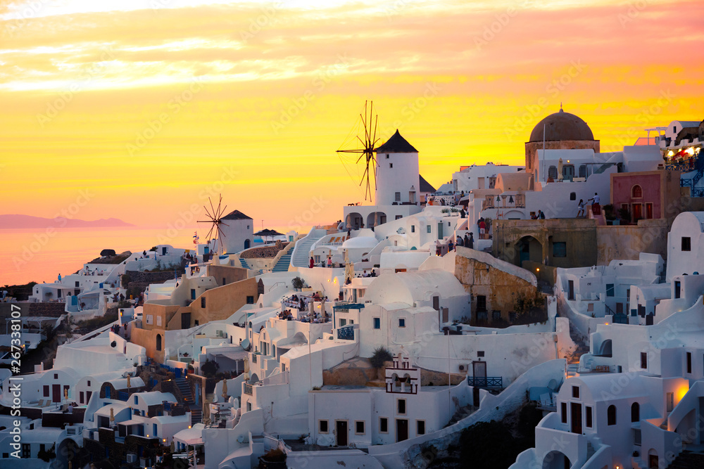 Brilliant sunset illuminating the white washed houses and windmills in Oia, Santorini, Greece