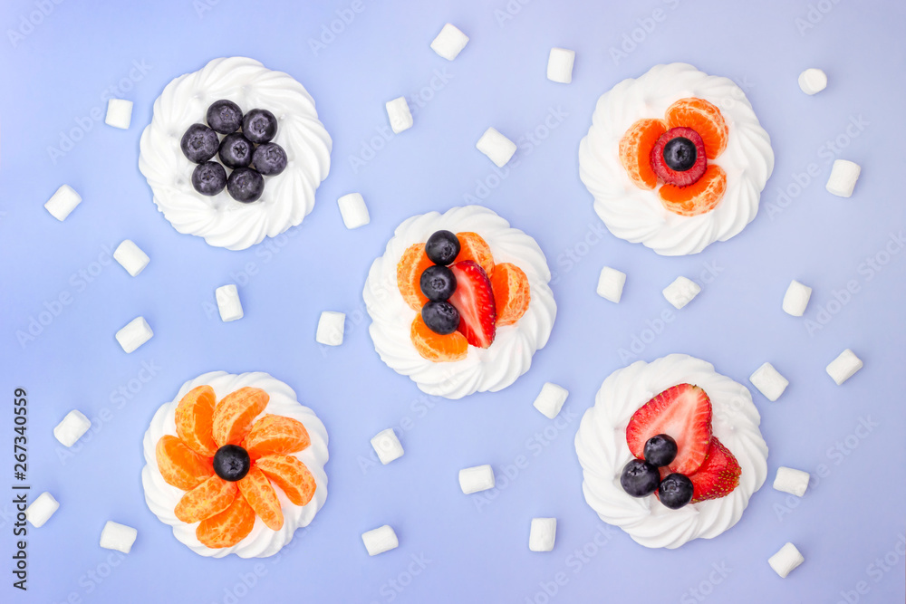 Meringue and marshmallow with berries on a lavender background. Top view