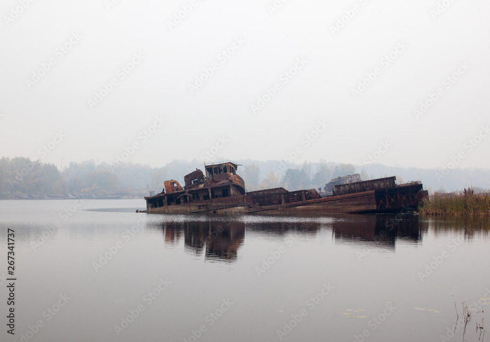 Old sunken ship in water in a foggy day