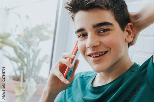 portrait of a male teenager with braces and mobile phone photo