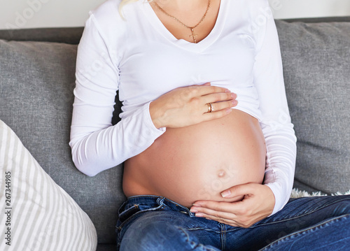 Pregnant girl on a light background. Photo without a face in the frame.