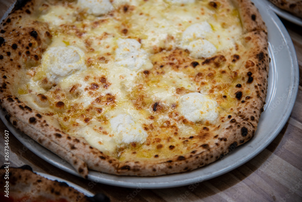 Four cheese pizza (Quattro Formaggio) on wooden table, Italian cuisine in Vancouver, Canada Four cheese pizza (Quattro Formaggio) on wooden table, Italian cuisine in Vancouver, Canada
