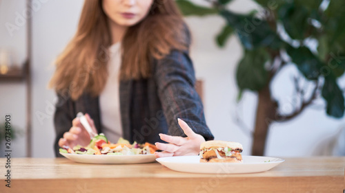 Pensive woman making decision between healthy food and fast food. healthy eating concept. business woman in a jacket having lunch at the office