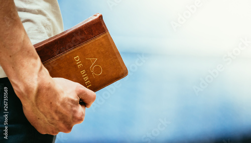 Fotografie Christian preacher: Young man is holding the bible, praying