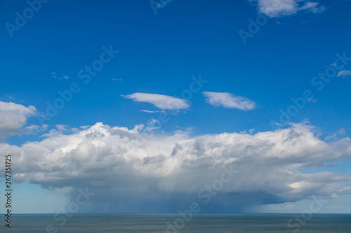 Rain clouds over the ocean with a blue sky above them