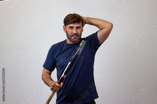 Portrait of handsome young man playing tennis holding a racket with brown hair looking overwhelmed, looking at the camera. Isolated on white background.