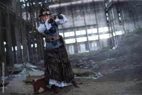 elderly lady in a steampunk costume at an abandoned factory with arms in hand