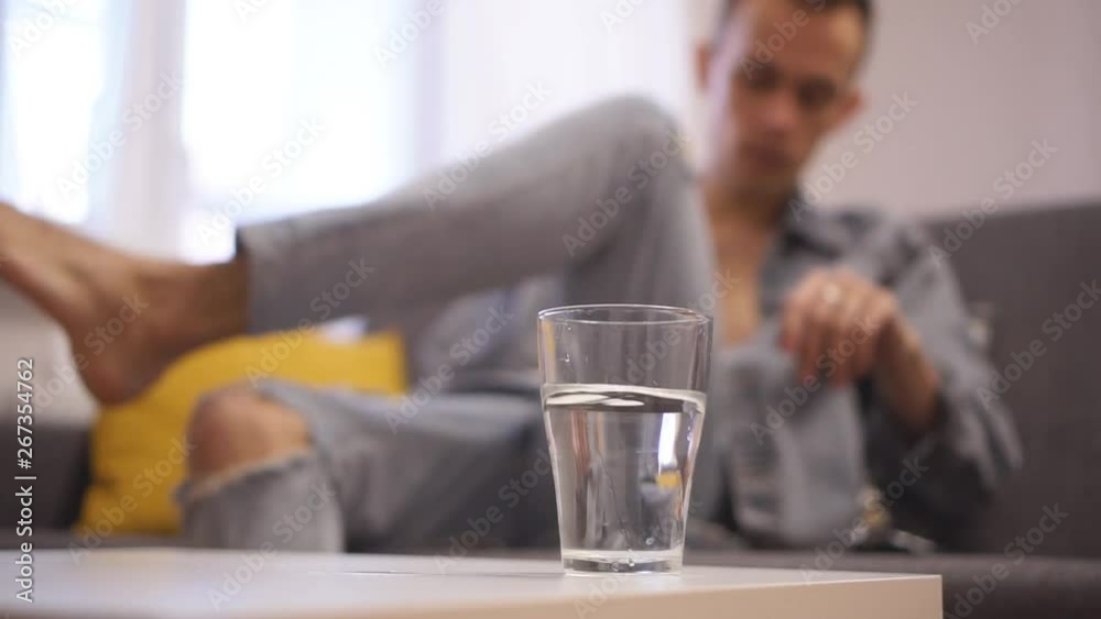 The guy drinks water. Watching TV and smoking a cigarette. Being at home. The guy drinks water. Watching TV and smoking a cigarette. Being at home.