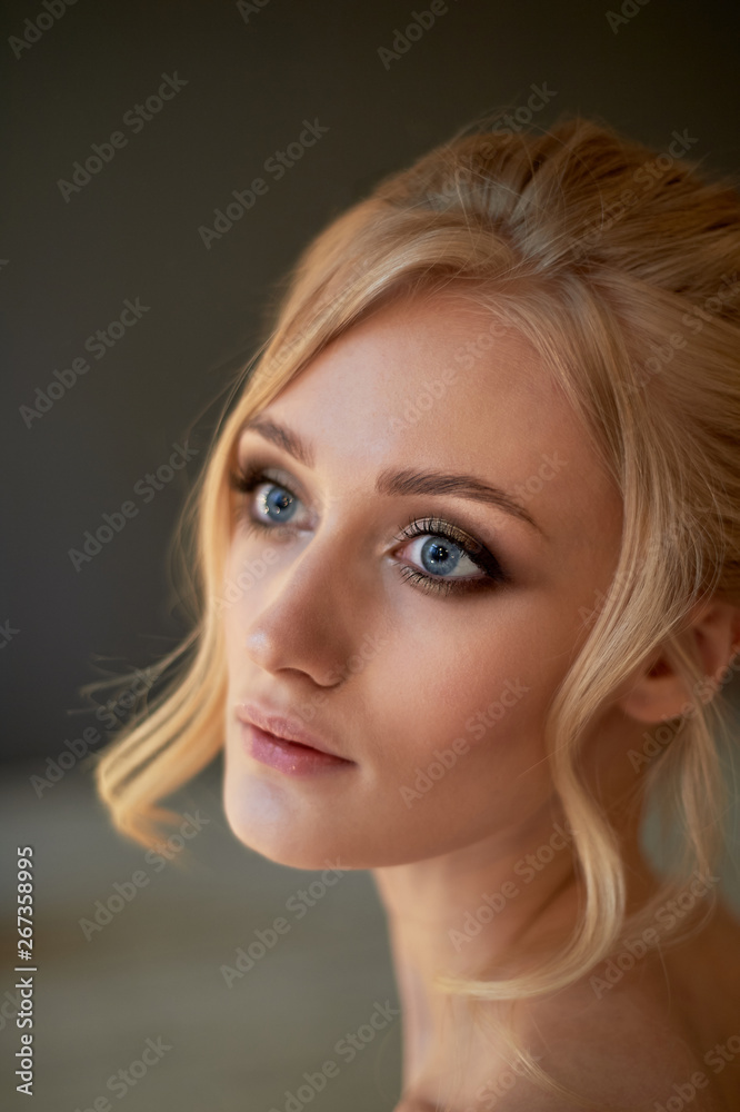 Naklejka premium Portrait of a beautiful miniature bride in a lace dress. Hair with curls. Emphasis in make-up on the eyes.Blonde