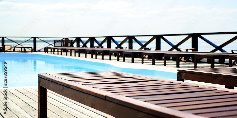 Wooden sun loungers by the pool. Near the sea.