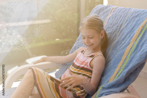 Teenager relaxes in a lounge chair with tablets in her hands