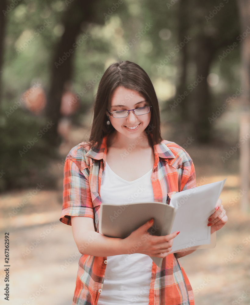 Obraz premium smiling student girl with a clipboard on the background of the Park