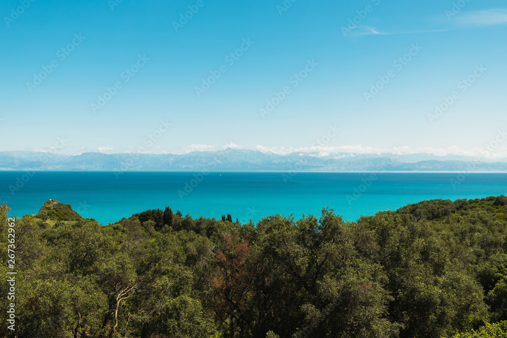 View from Cape Drastis (Peroulades) towards Albania and its mountains with crystal clear blue water on a sunny summer day (Corfu, Greece, Europe)