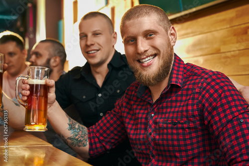 Male hipster keeping glass of beer and posing of fun