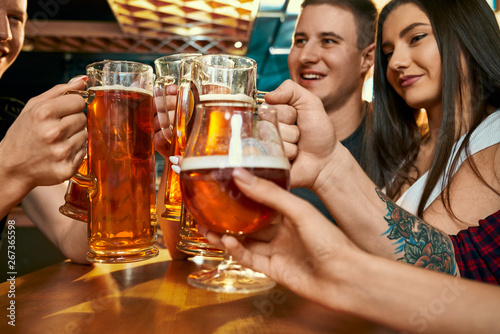 Selective focus of pints of beer in hands of friends in pub