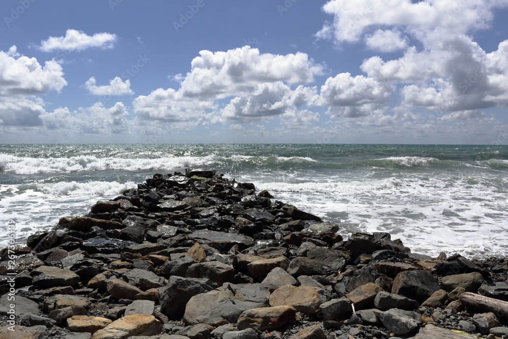 sea waves running on a stone Cape against the sky with white clouds