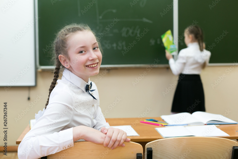 Cheerful schoolgirl indulges in a lesson. Girl schoolgirl turns back flirts, with classmate friend. Cheerful schoolgirl indulges in a lesson. Girl schoolgirl turns back flirts, with classmate friend.