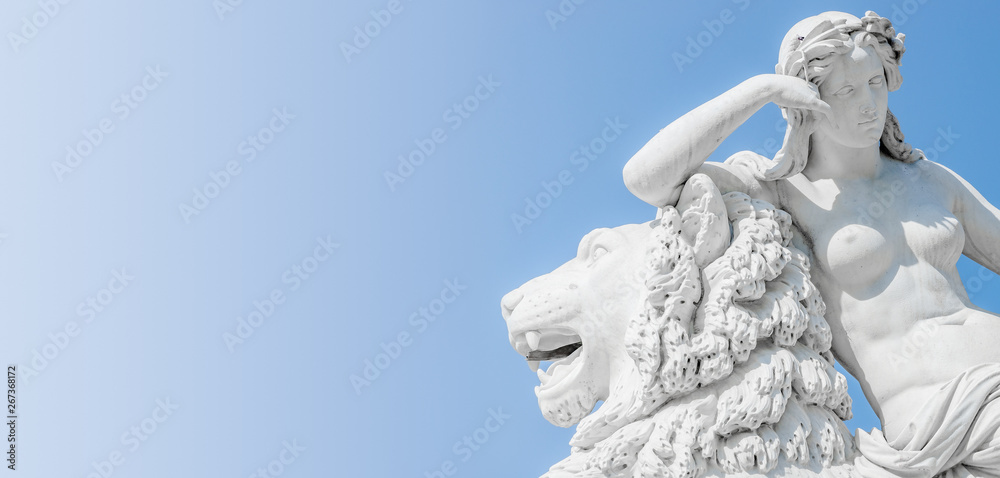 Banner of an ancient statue sensual Renaissance Era woman laying on big lion with blue sky gradient background in Potsdam, Germany, details, closeup