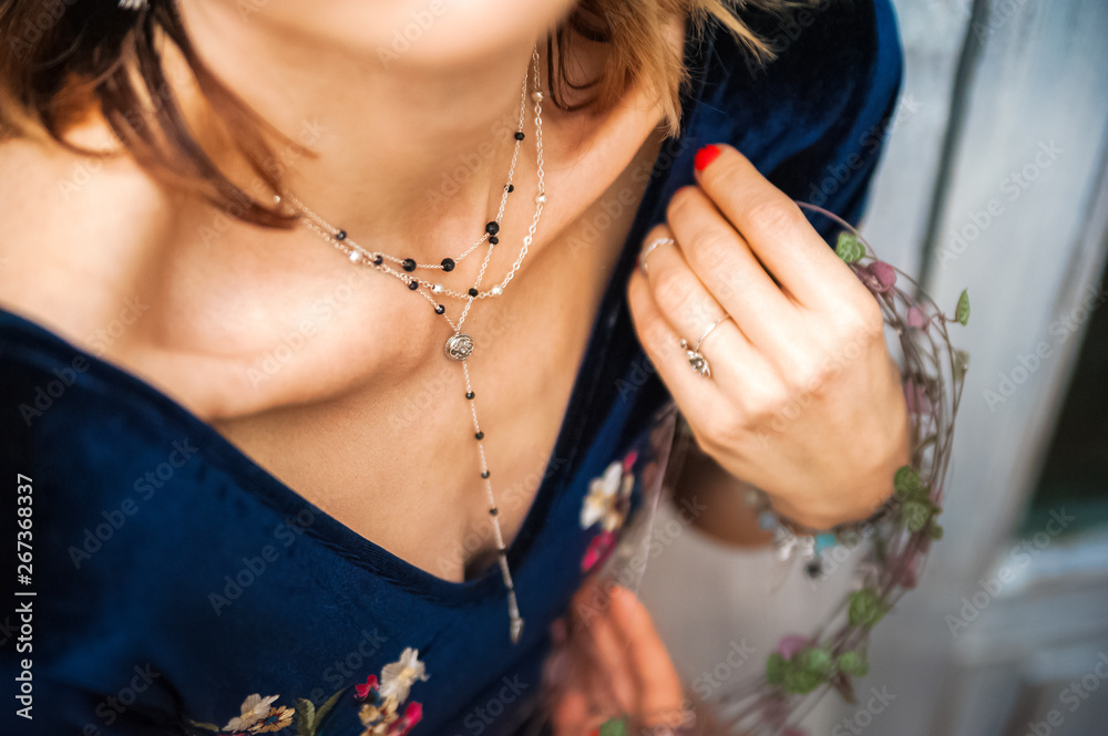 Female neck and collarbone with beautiful chain close up and copy space. Woman in a blue velor bodysuit, in a defocus Ceropegia woodii