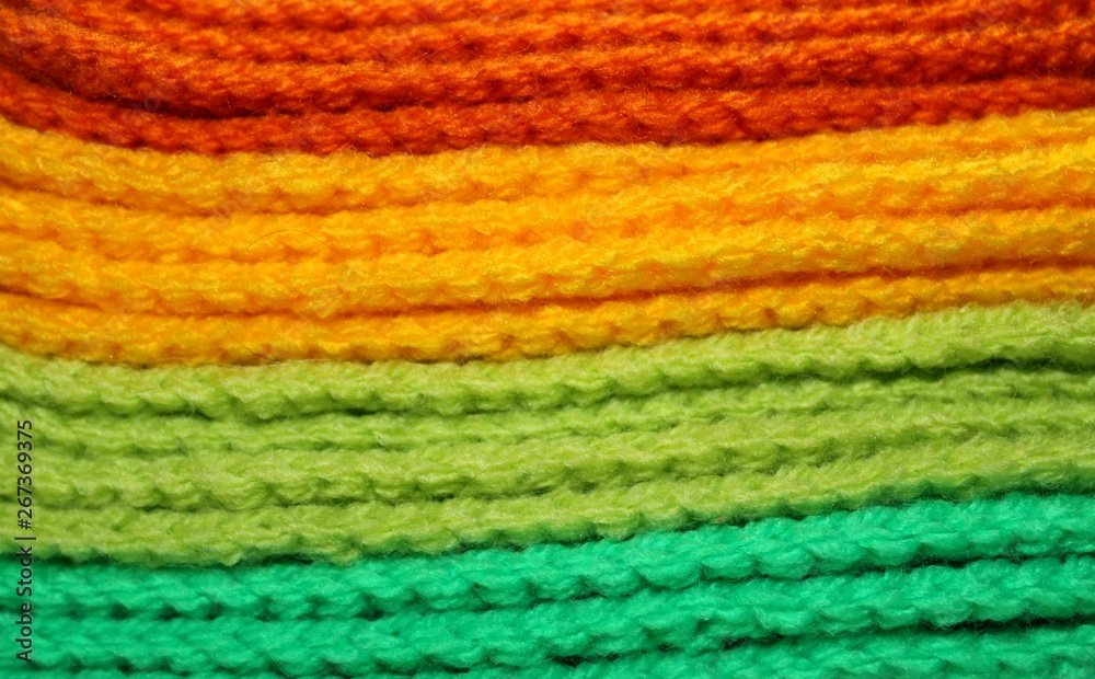 Colorful orange, yellow and green design background of knitted woolen elements in a pale