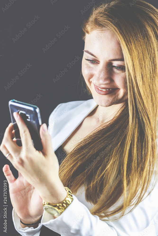 Junge Frau mit Jeans und weißem Blazer lächelt und hält Ihr Smartphone in der Hand, telefoniert und liest Nachrichten. Junge Frau mit Jeans und weißem Blazer lächelt und hält Ihr Smartphone in der Hand, telefoniert und liest Nachrichten.