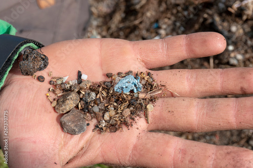 Child holding micro plastic pollution in soil found by the beach