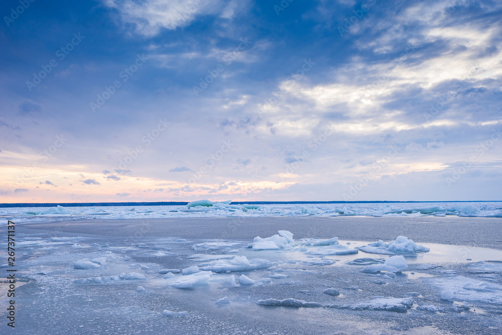 Fototapeta premium Beach in wintertime. Frozen sea, evening light and icy weather on shore like fairy tale country. Winter on coast. Blue sky, white snow, ice covers the land.