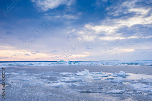 Beach in wintertime. Frozen sea, evening light and icy weather on shore like fairy tale country. Winter on coast. Blue sky, white snow, ice covers the land.