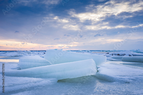 Beach in wintertime. Frozen sea, evening light and icy weather on shore like fairy tale country. Winter on coast. Blue sky, white snow, ice covers the land.