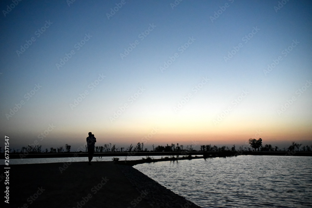 Silhouette Man and Baby at Lake on the sunset at Al Qudra love lake, Dubai, United Arab Emirates
