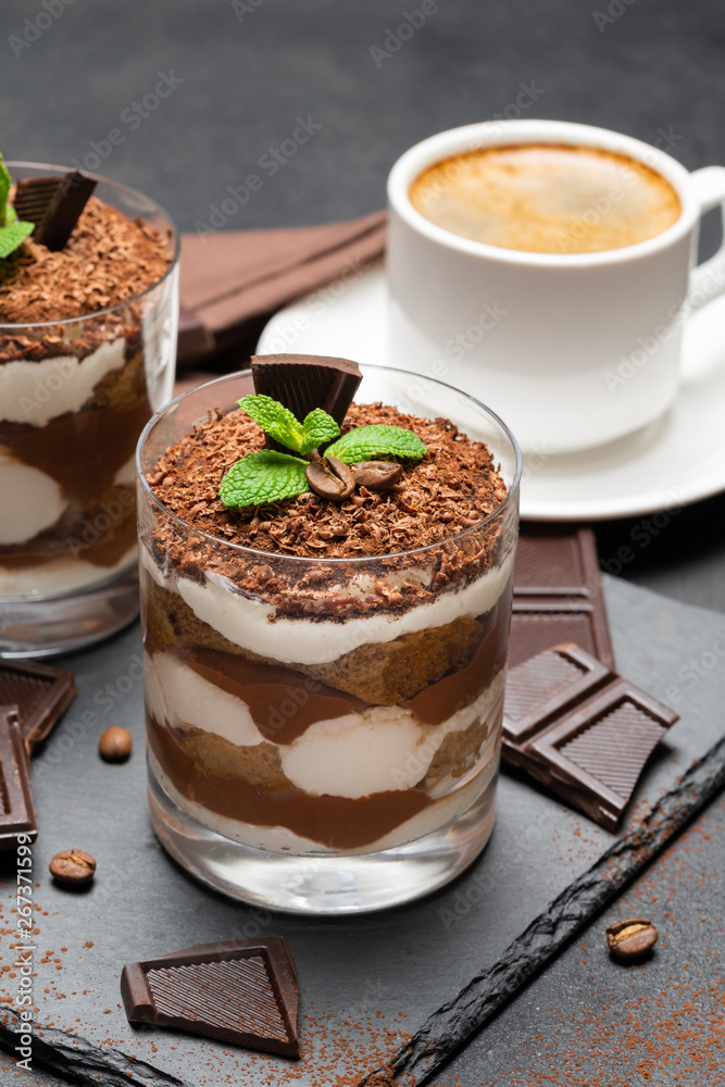 Classic tiramisu dessert in a glass and cup of coffee on dark concrete background Classic tiramisu dessert in a glass and cup of coffee on dark concrete background