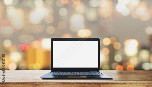 Computer laptop blank white screen on wooden desk, with blurry Bokeh light background