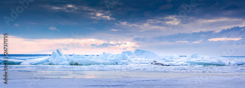 Beach in wintertime. Frozen sea, evening light and icy weather on shore like fairy tale country. Winter on coast. Blue sky, white snow, ice covers the land.