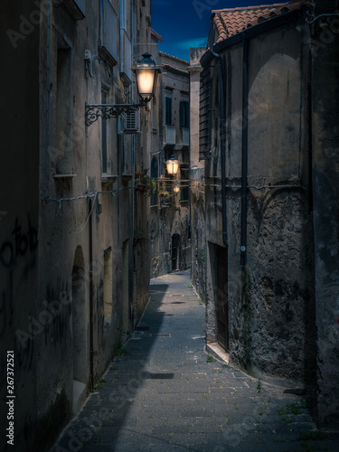 Streets of Tropea in Italy in dark night or evening. Bright lanterns lamps lit up the old buildnings and narrow pathways.
