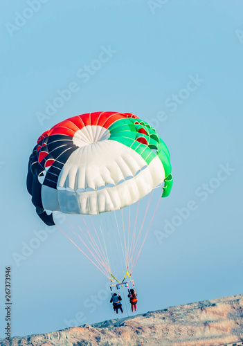 Fototapeta Naklejka Na Ścianę i Meble -  Couples doing paragliding water sport in blue water sea at beach
