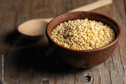 couscous croup in a clay bowl on a wooden background